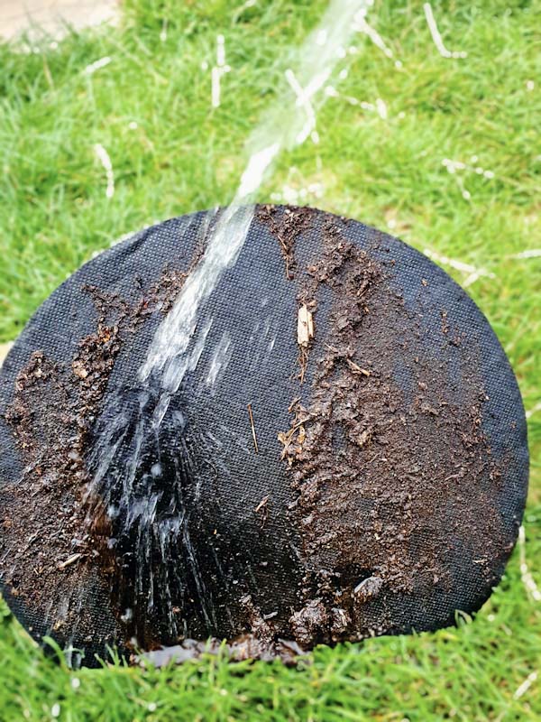 HydRoot Base Insert for Tree Planting Bags, surface mud being cleaned with water
