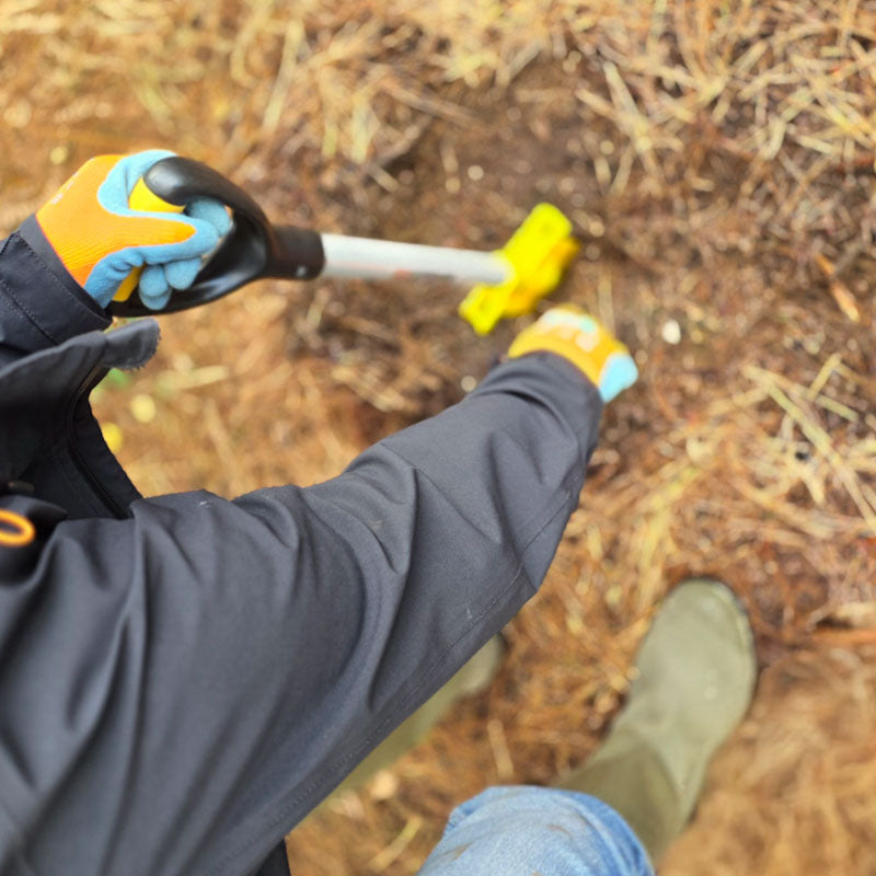 Man bending to plant a tree sapling with PLANTEM Short tool in woodland